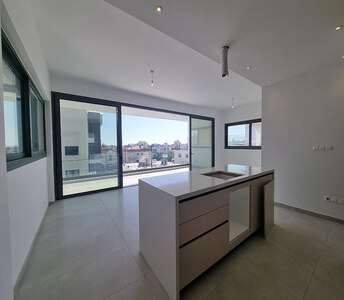 Spacious open-plan area with central island, recessed lighting, and access to a large covered balcony with urban views