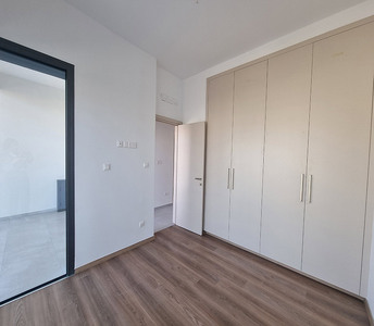 Bedroom with built-in wardrobes, wood-style flooring, and access to the balcony through sliding glass door
