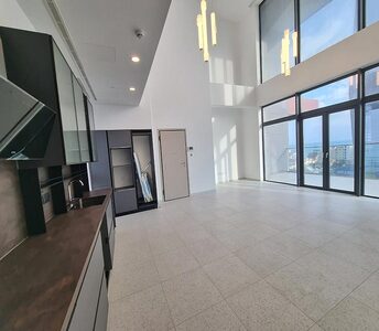 Comfortable living area with modern kitchen, high ceilings, and expansive windows offering panoramic views