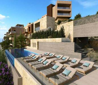 Hillside residential development in Agios Tychonas with infinity pool, natural stone cladding and panoramic layout