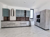 Kitchen of the apartment in Limassol with matte grey cabinetry, built-in appliances, and contrasting dark wood backsplash